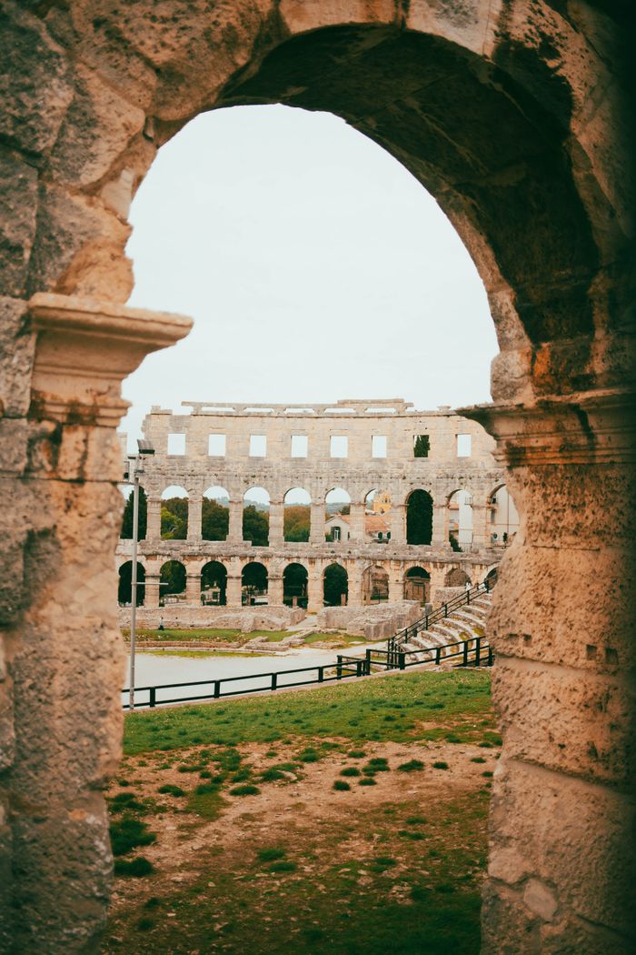 Explore the ancient Roman amphitheater in Pula, Croatia, through its iconic stone arches and historical architecture.