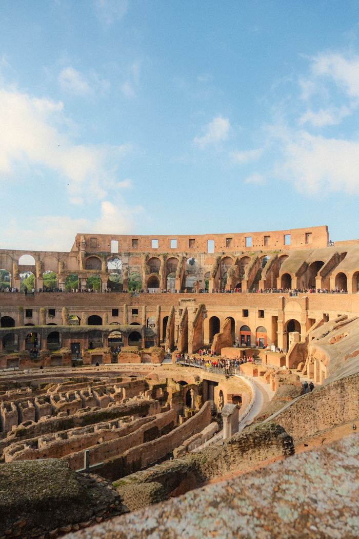 Explore the ancient architecture of Rome's Colosseum under a clear blue sky.