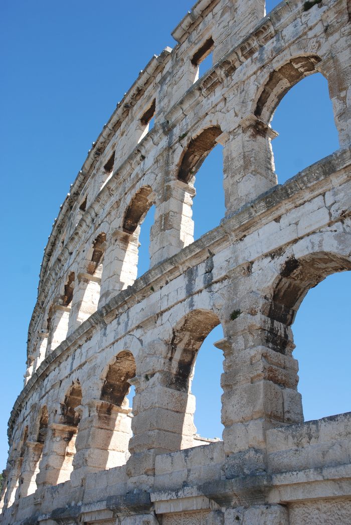 Stunning view of the ancient Roman amphitheater in Pula, Croatia against a clear blue sky.