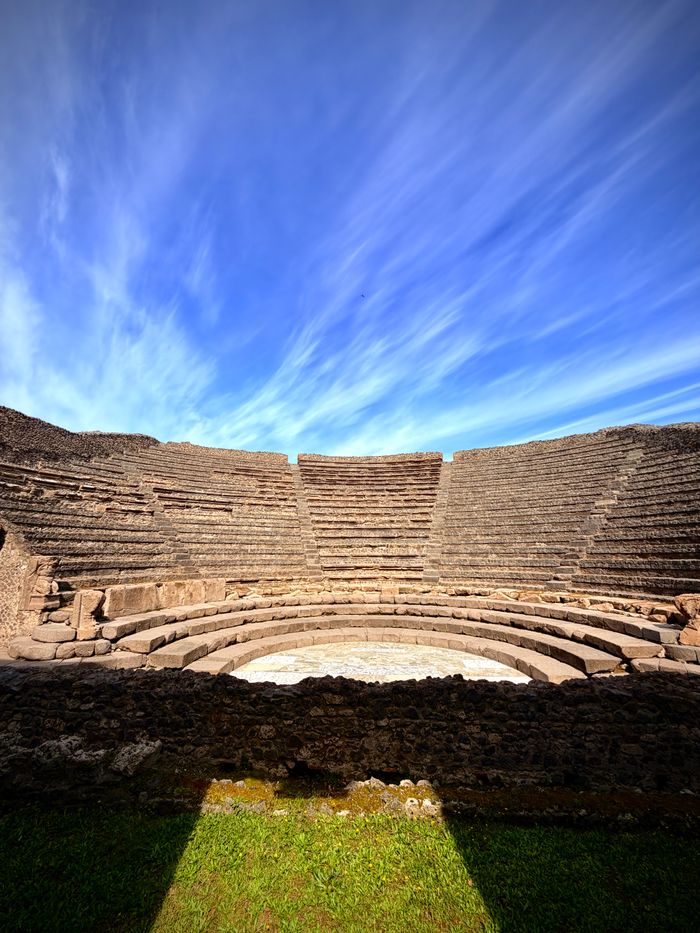 Explore the timeless beauty of an ancient Roman amphitheatre with a dramatic sky backdrop, captured in Pompeii.