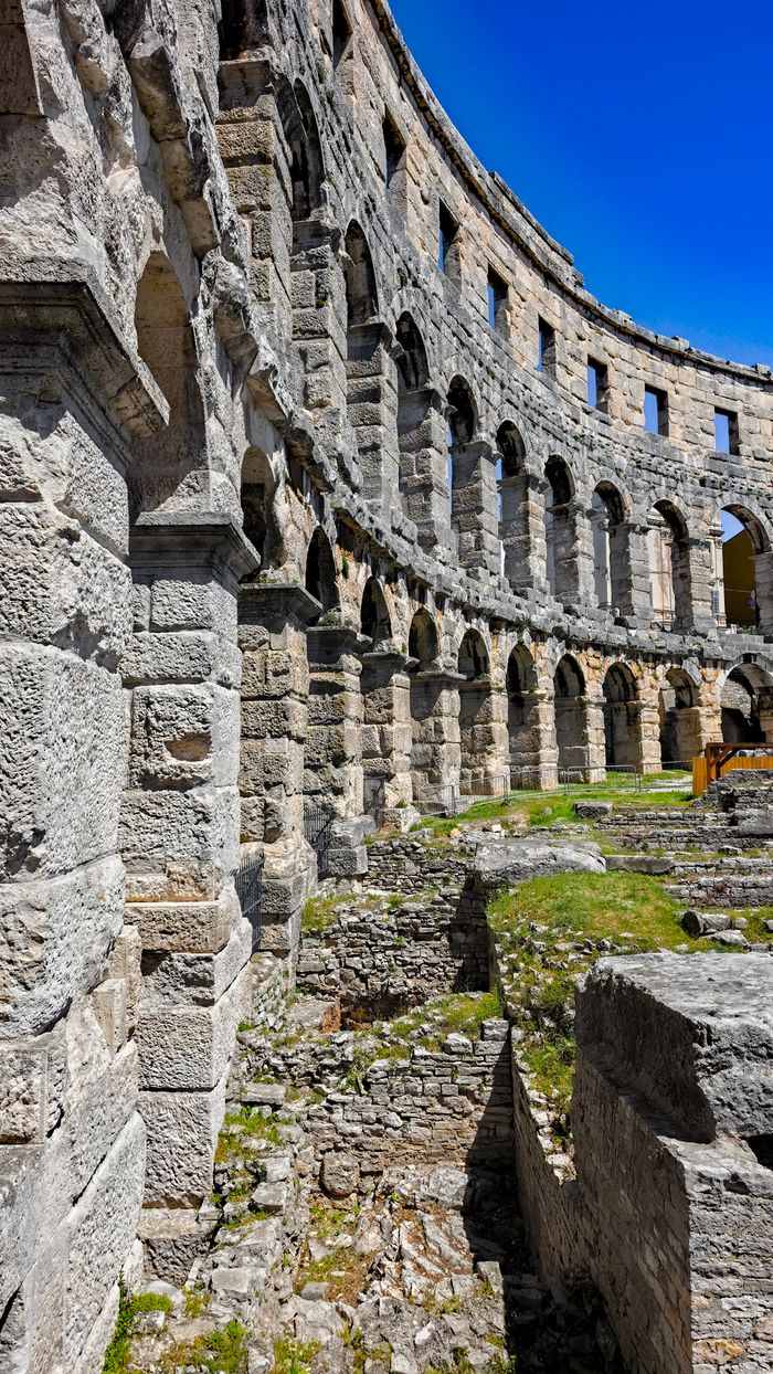 Explore the historic stone arches of the Roman amphitheater in Pula, Croatia.